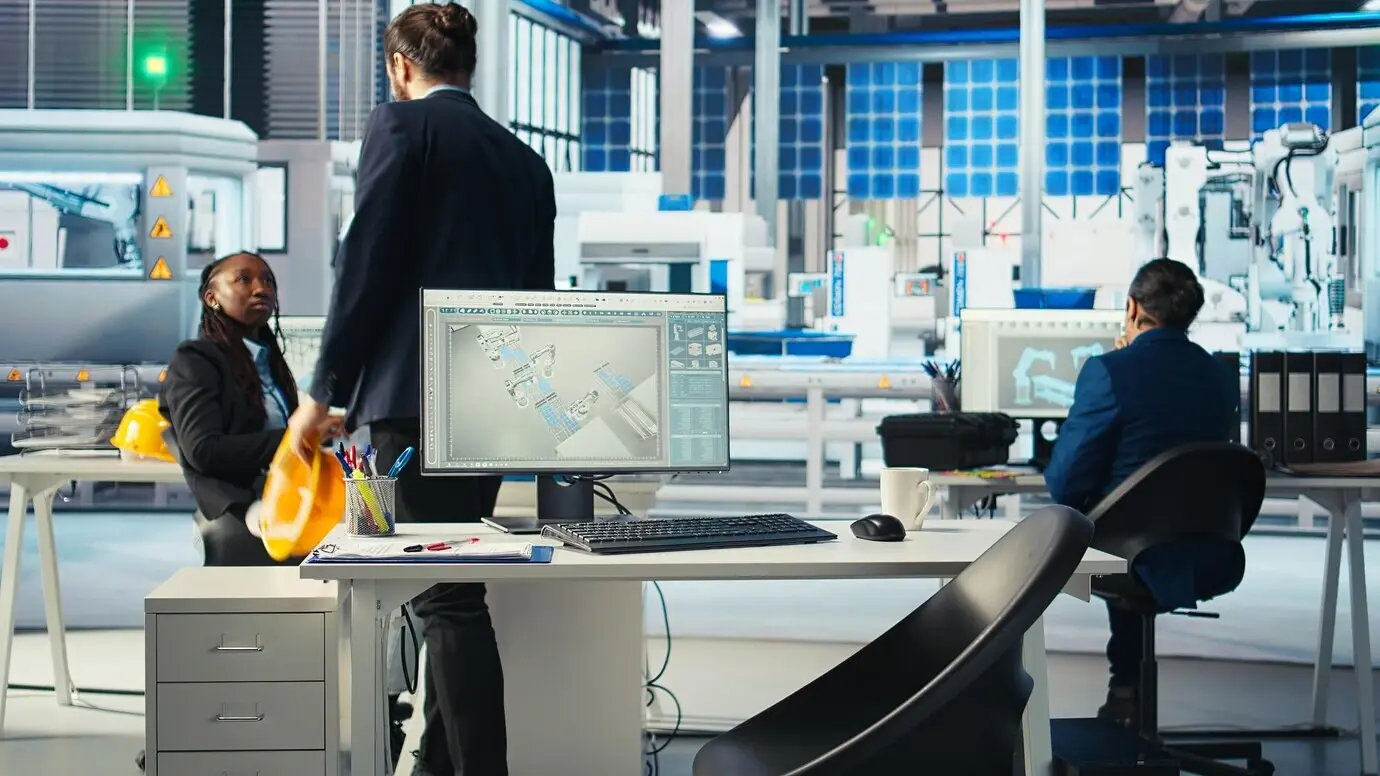 Менеджер, пришедший на работу в офис фотовольтаического завода, анализирует данные на компьютере.